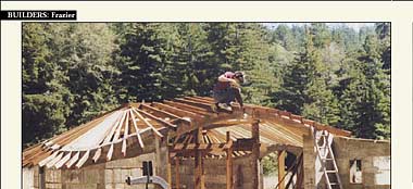 Framing shop roof. No floor yet. Walls are covered with foam insulation on outside. Dark vertical and horizontal lines indicate structural grid of building, with 4H" bars of steel. (Insulation is flush with exterior of grid.) See drawings below for details.