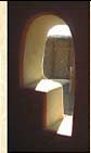 Arched window in straw bale walls, clay-plastered wall finished with red wax and pigment. Interior of window is white clay plaster with micaceous sand.
